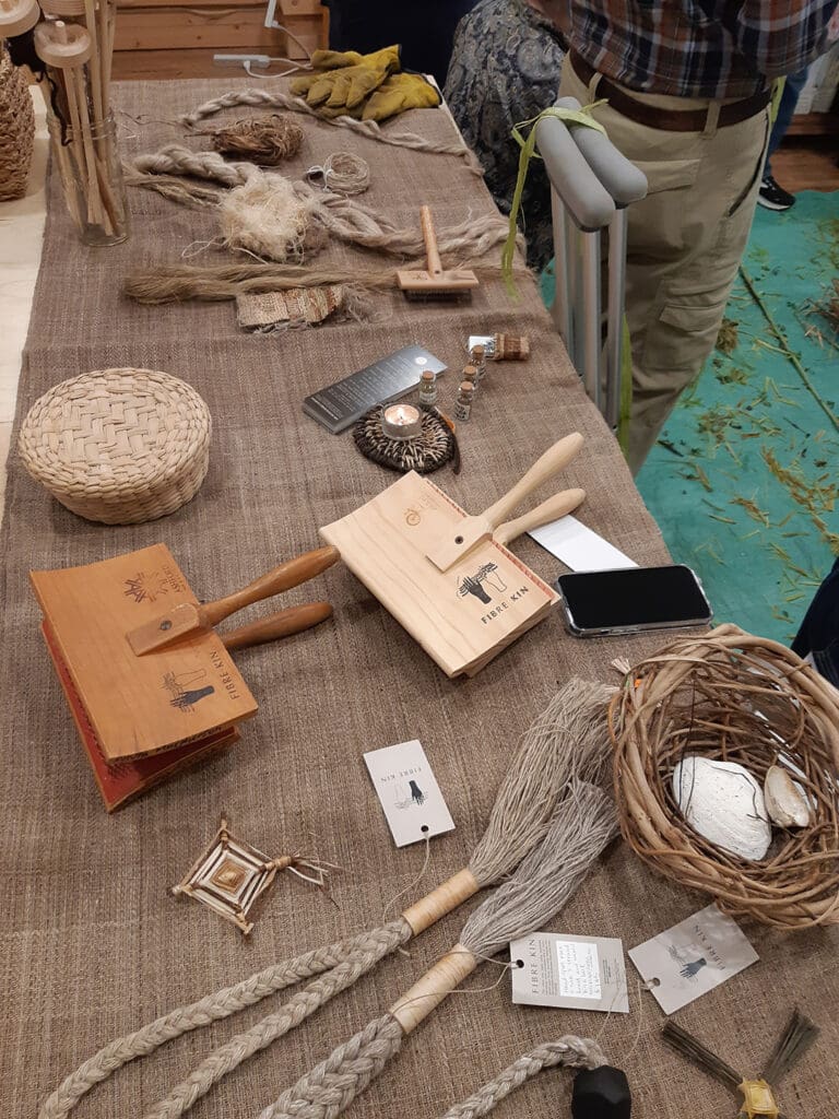 linen covered table with hand carders and examples of goods made with nettles