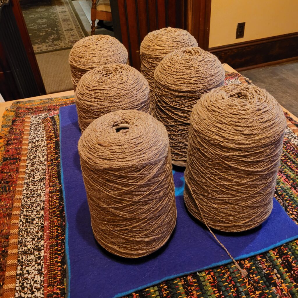 6 large cones of brown wool on a blue mat. 