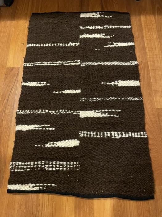 Rug on wood floor made with Brown and white plainweave wool on hemp warp