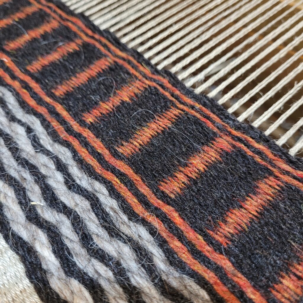 boundweave rug in brown, orange, and light grey on the loom
